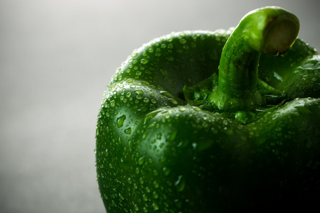 Close up of green bell pepper with water droplets over grey backgroundの写真素材