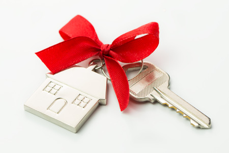 House key with red bow over white backgroundの写真素材