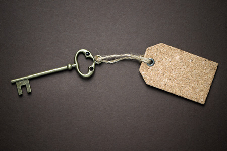 Door key tied with blank label over brown backgroundの写真素材