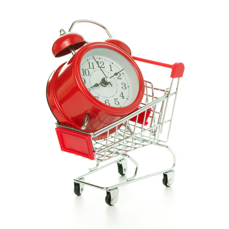 Red classic alarm clock in a shopping cart isolated on white backgroundの写真素材