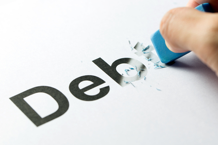 Close up of blue rubber eraser erasing the word debtの写真素材
