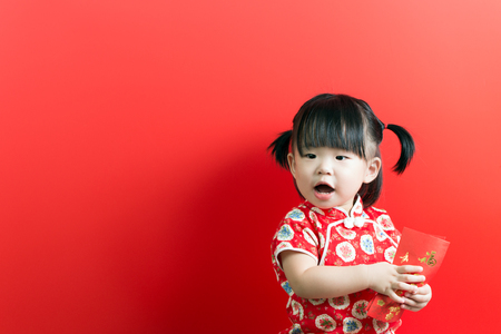 Little Asian girl holding red envelope on red background