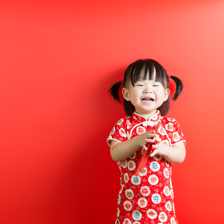 Little Asian girl holding red envelope on red backgroundの写真素材