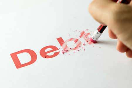 Close up of red pencil erasing the word debt on paper