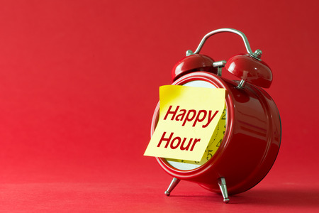 Happy hour words written on sticky yellow note with red classic clockの写真素材