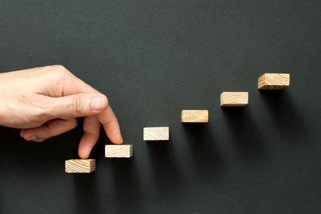 Fingers going up wooden stairway over black backgroundの写真素材