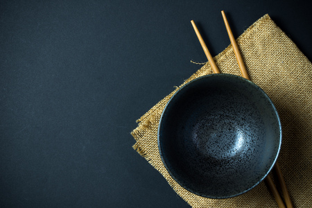 Japanese empty bowl with a pair of chopsticks isolated on black backgroundの写真素材