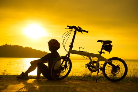 Silhouette of cyclist at sunset or sunrise near oceanの写真素材