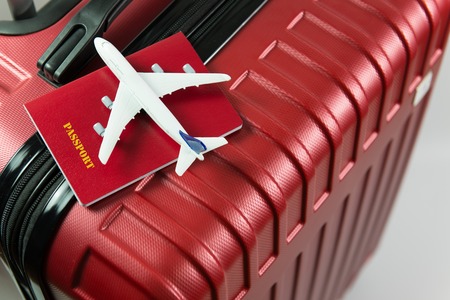 Red passport and airplane small model on red luggage for travel conceptの写真素材