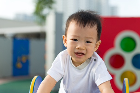 Adorable little Asian baby boy having fun on playgroundの写真素材