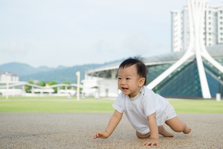 Beautiful baby boy crawling outdoor in park, learn to walkの写真素材