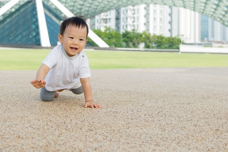 Beautiful baby boy crawling outdoor in park, learn to walkの写真素材