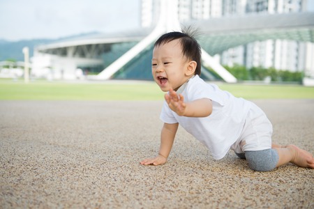 Beautiful baby boy crawling outdoor in park, learn to walkの写真素材