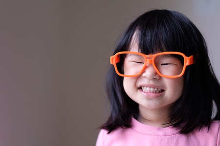 Funny little asian child with a pair of big orange glassesの写真素材