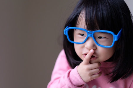 Funny little asian child with a pair of big blue glassesの写真素材