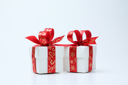 Two white gift boxes tied with Christmas theme red ribbon isolated on white backgroundの写真素材