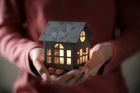 Miniature house model with illuminated light in the handの写真素材