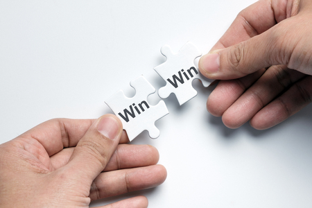 Hand putting two pieces puzzle together with word win win situationの写真素材