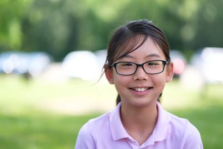 Asian Chinese girl with eyeglasses portrait smiling in park