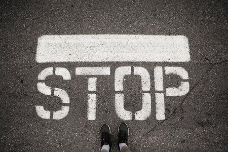 White stop sign on the ground in front of feetsの写真素材