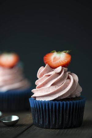 Chocolate cupcakes with strawberry meringue butter cream on a wooden tableの写真素材