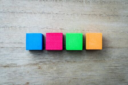 Red, blue, green and orange color square blocks isolated on wood textured backgroundの写真素材