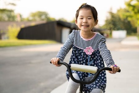 Cute little Asian girl learning ride a bicycle without wearing a helmetの写真素材