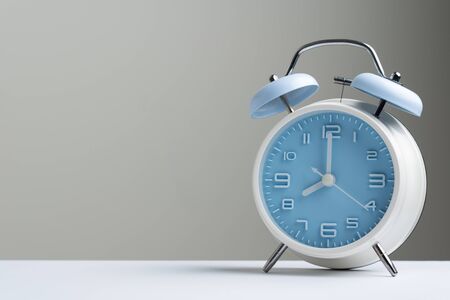 Blue color old fashioned bell alarm clock showing 8 o'clock isolated on white background