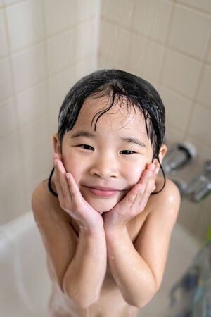 Cute four year old girl taking a relaxing bath with foam in bathroomの写真素材