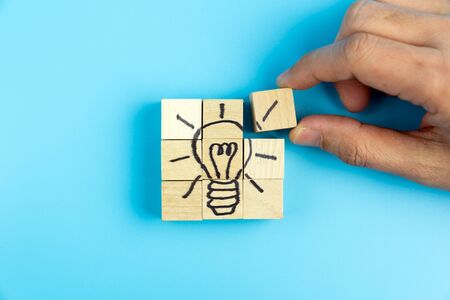 Hand puting together wood blocks to form a lightbulb picture for creativity, innovation or idea...