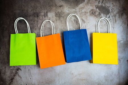 Four colorful shopping bags in a row isolated on dark grungeの写真素材