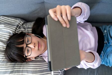 Female Asian teenager using digital tablet indoors at homeの写真素材