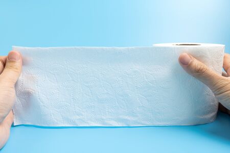 Hand hold one toilet paper roll isolated on blue backgroundの写真素材