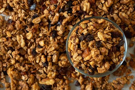 Healthy granola cereal with oats, pumpkin seeds, walnuts, and raisins in a glass bowl