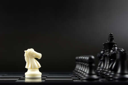 One white knight chess piece facing all black chess pieces for fierce competition situation, one against many conceptの写真素材
