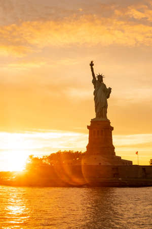 The Statue of Liberty at New York city during sunset with reflections on the oceanの写真素材