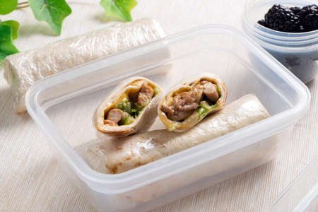 Healthy lunch box with sandwich wrap and grape in plastic container