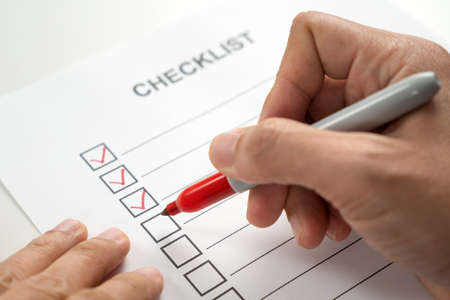 Hand with red marker pen marking on checklist sheet