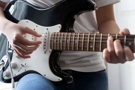 Young girl playing electric guitar in close up detailの写真素材