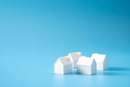Miniature 3D printed model house on blue background for home or real estate marketの写真素材