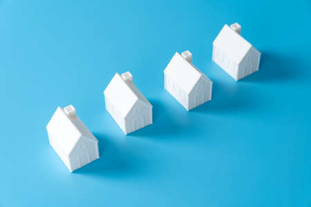 Miniature 3D printed model house on blue background for home or real estate marketの写真素材