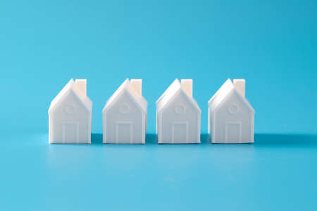 Miniature 3D printed model house on blue background for home or real estate marketの写真素材