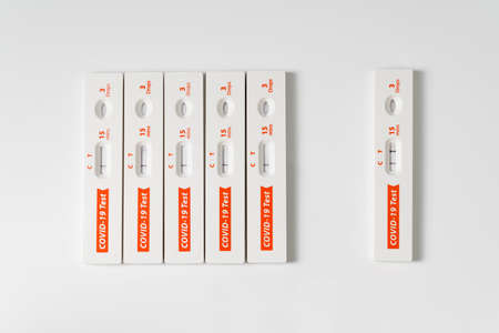 Row of rapid antigen test kit for covid-19 and one is positive isolated from the rest of negative test kits for quarantine conceptの写真素材