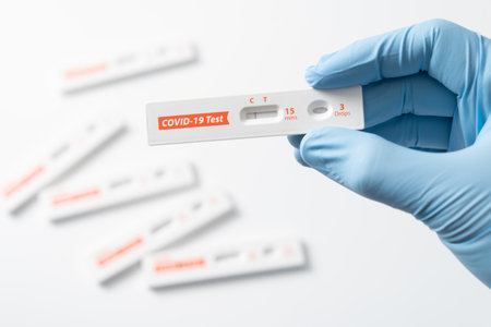 Hand with glove is showing negative results on test strip for rapid antigen home Covid-19 test kit...