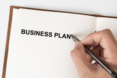 Business Plan text with a person holding a pen on a note bookの写真素材