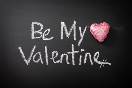 Be My Valentine written in chalk on blackboard with glittery pink heartの写真素材