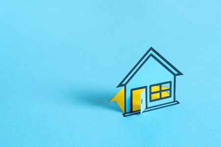 Blue colored papered house on blank blue backgroundの写真素材