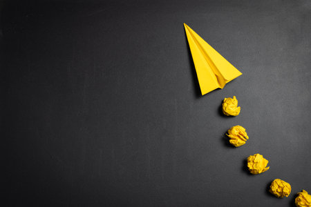 Top down view yellow paper origami airplane flying isolated on blackboard, for concepts of leadership, unique, innovation, business success, marketing, growth, travel, freedom, dream.の写真素材