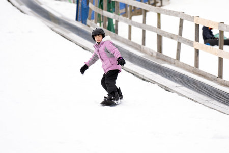 Action motion photo of an Asian female child snowboarder on mountain ski slope doing free snowboarding style.の写真素材