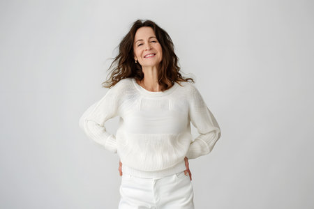 Beautiful confident mature middle aged 40s woman smiling looking at camera posing isolated on white grey studio backgroundの素材